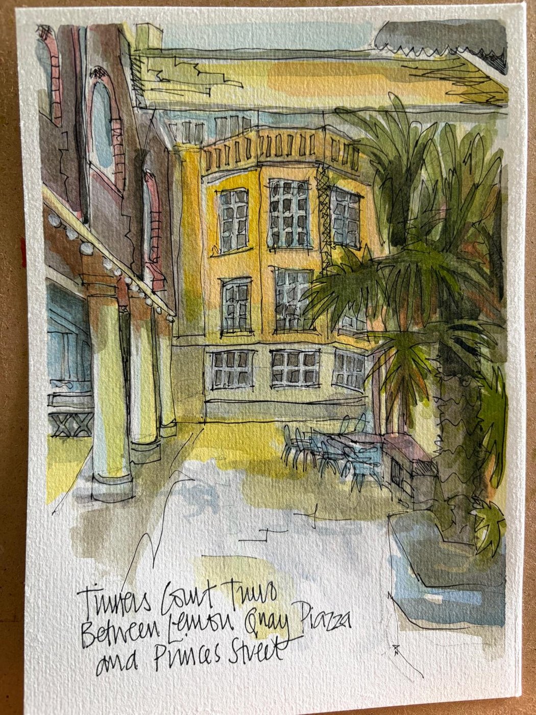 Kat’s ink and wash of Tinners Court in Truro: a yellow building, a palm, tables, handwritten caption