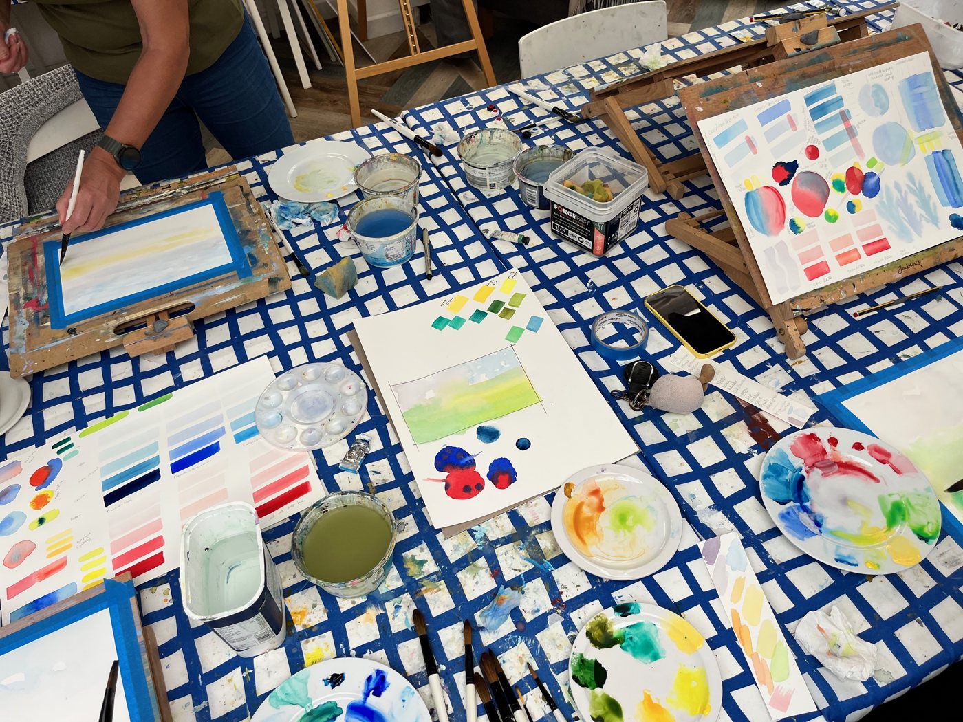 The table mid-session: swatches, mixing palettes and first washes