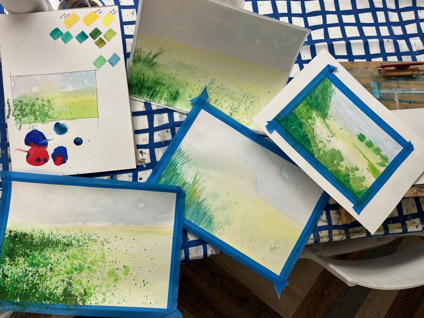 A row of small loose watercolour landscapes in greens and yellows
