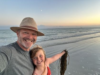 Carrying seaweed up the beach at sunset