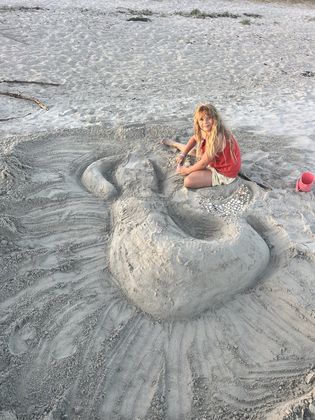 Amélie beside the finished mermaid, the tide coming for it