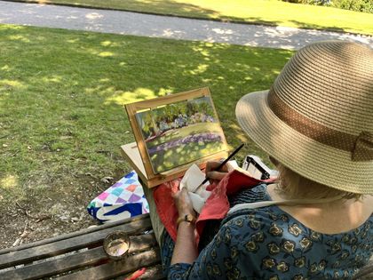 Over the shoulder of a painter at work in a straw hat