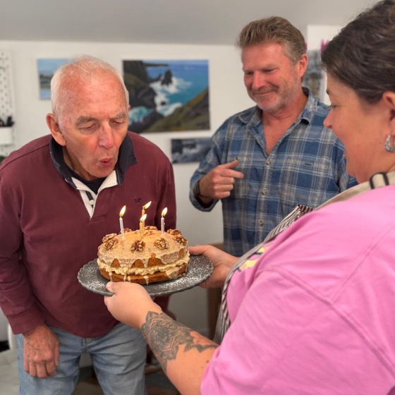 Roger blowing out the candles on a coffee and walnut cake