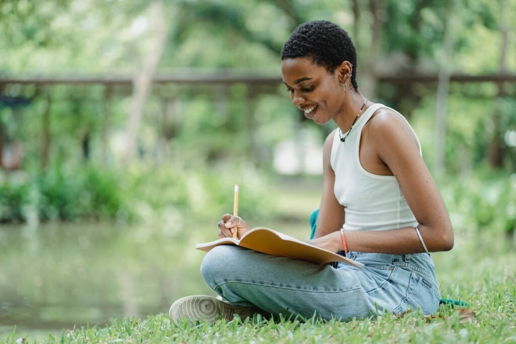 A young woman sitting on the grass sketching in a park